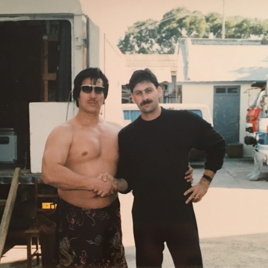 Two men standing next to each other in front of a truck.