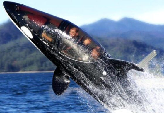 A man is jumping out of a black orca whale, showcasing one of the cool gadgets for spoiled millionaires.