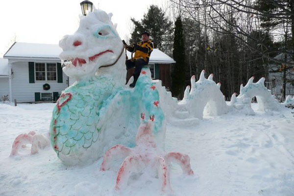 A man atop a dragon snow sculpture.