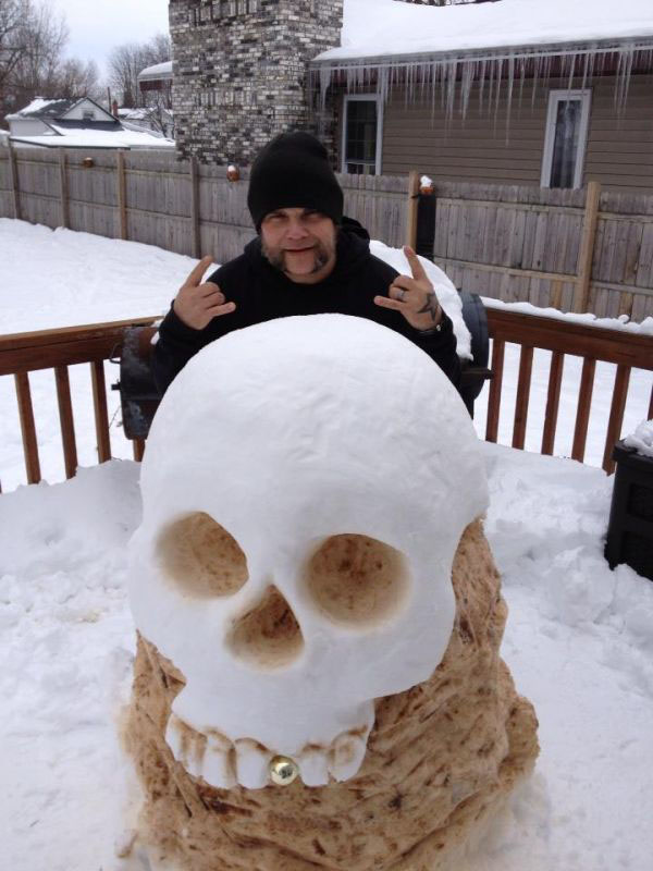 A man is posing next to a snow sculpture.