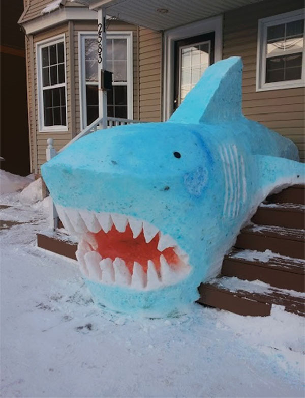 A snow shark sculpture adorns the home's steps, showcasing the beauty of winter artistry.