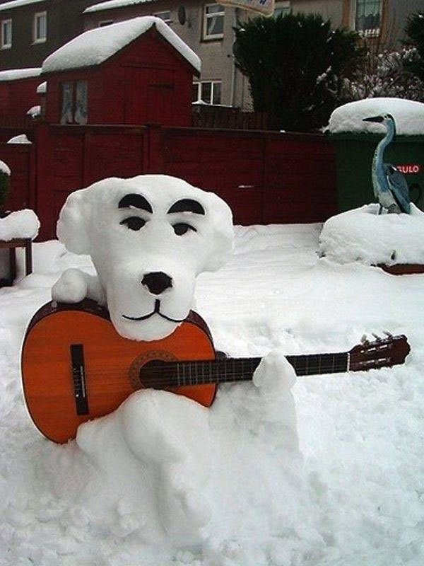 A snow sculpture of a dog playing an acoustic guitar that brings joy during the winter.