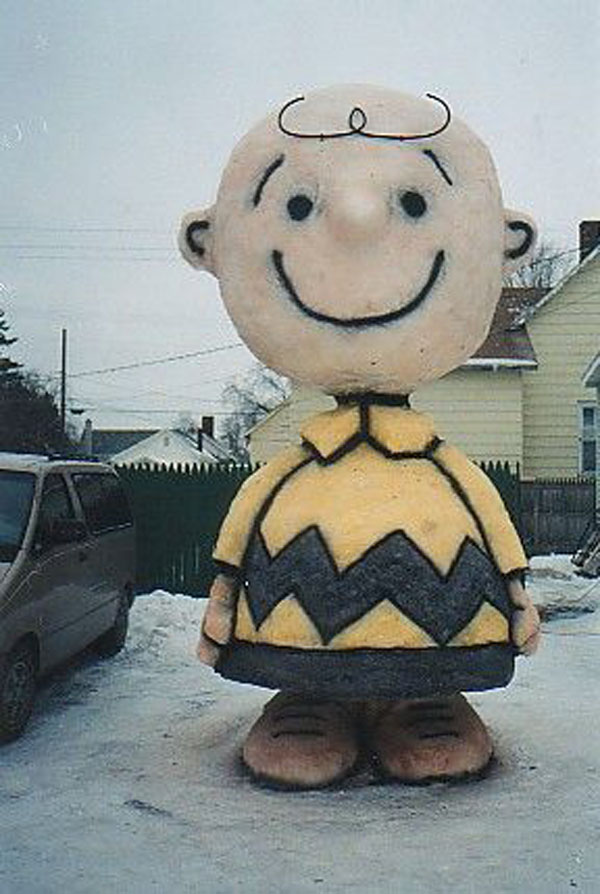 A statue of Charlie Brown standing in front of a house, capturing the winter essence.