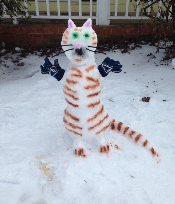 A cat sculpture in the snow brings winter joy.