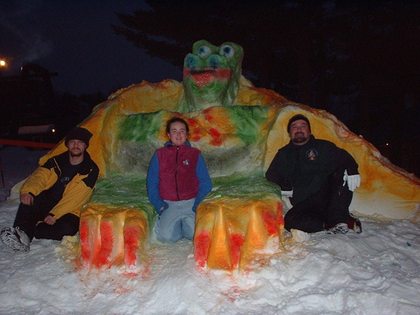 Three people posing in front of an ice sculpture, showcasing the mesmerizing snow art.