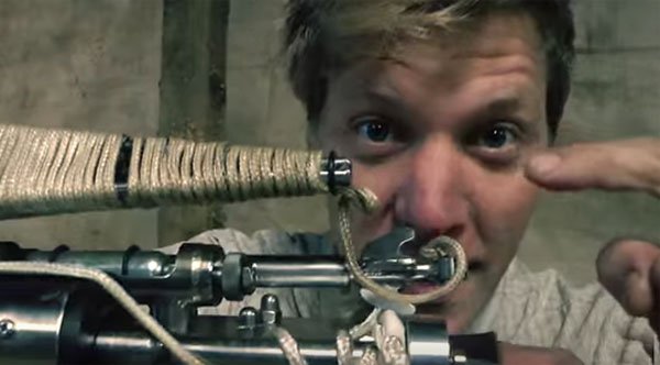 A man constructs a rope launcher machine.