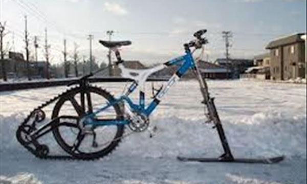A bicycle parked in the snow next to a train embodies the struggle between wants and needs.