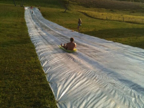 A group of people enjoying a thrilling water slide adventure in a grassy field.