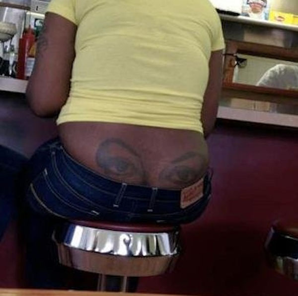 A woman displaying a back tattoo at the bar.