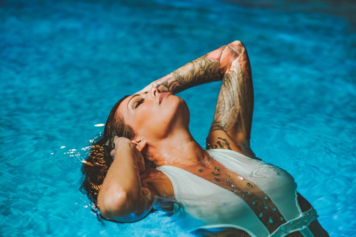 A woman with hot tattoos relaxing in a swimming pool.