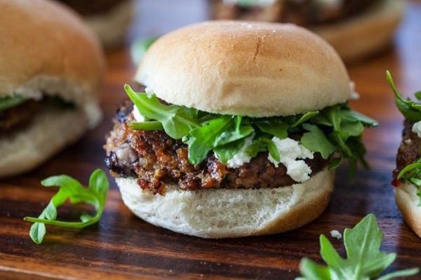 Meatball sliders with feta and arugula, perfect for Super Bowl, beautifully presented on a wooden cutting board.