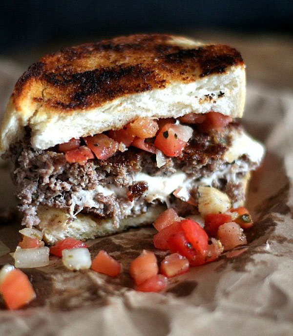 A visually enticing grilled Super Bowl burger with savory meat and fresh tomatoes.