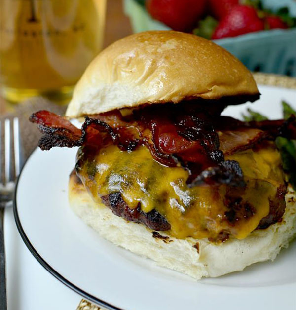 An awesome Super Bowl burger with bacon and cheese served on a plate.