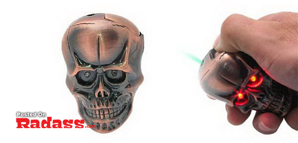 A hand stylishly lights up a metal skull with a red light on it.