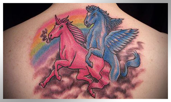 A woman's back tattoo featuring two unicorns and a vibrant rainbow.