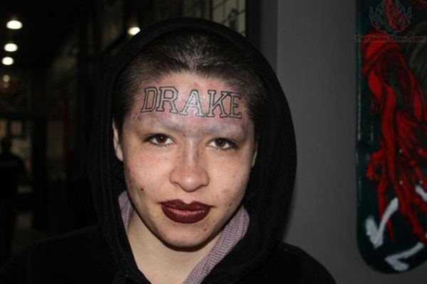 A woman wearing a hoodie with a head tattoo featured in 20 Terrible Tattoos That Will Make You Happy You Are You.