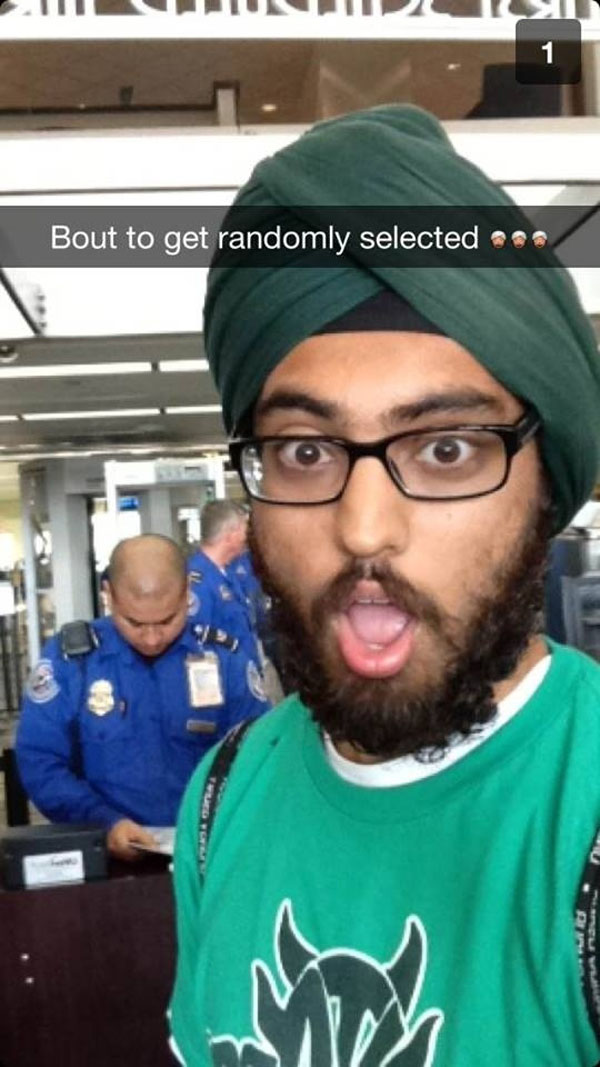 A man in a green turban is making a funny face while doing Snapchat.