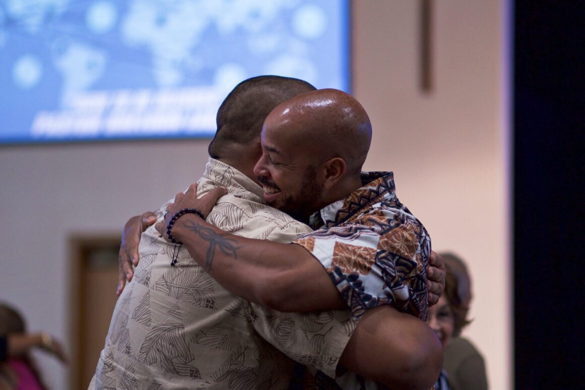 A man embraces another man, illustrating the importance of creating a lasting impression on your girlfriend's parents.