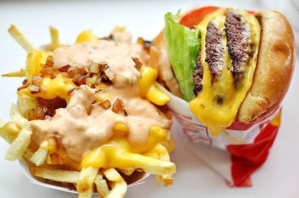 A mouthwatering McDonald's burger topped with golden fries and smothered in creamy cheese sauce.