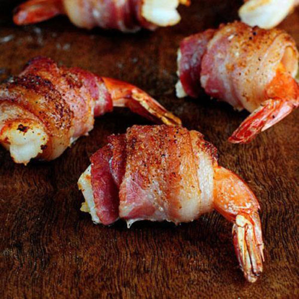 Bacon wrapped shrimp tantalizingly presented on a cutting board.