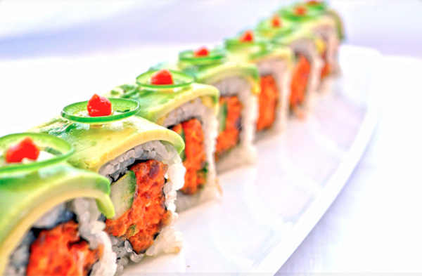 An avocado and carrot-topped sushi roll that is pure food porn.