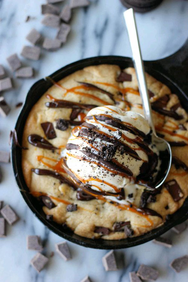 A delectable skillet cookie topped with creamy ice cream and adorned with gooey chocolate chips, perfect for indulging in some irresistible food porn.