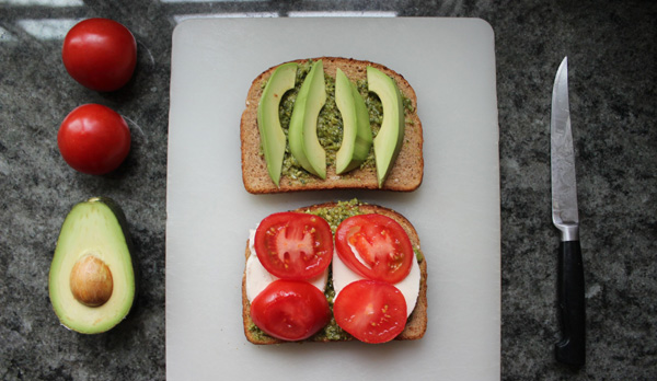 Two mouthwatering slices of toast adorned with fresh tomatoes and creamy avocados, captured on a cutting board - food porn at its finest.