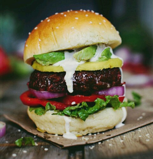 A mouthwatering burger loaded with avocado, lettuce, and tomatoes.