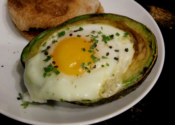 A tantalizing dish featuring a fried egg nestled within a luscious avocado, perfect for food porn enthusiasts.