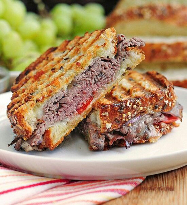 Hungry? How 'bout a mouth-watering grilled sandwich with meat and grapes on a plate.