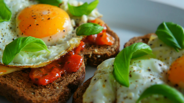 An enticing plate of toast adorned with a luscious egg and succulent tomato.
