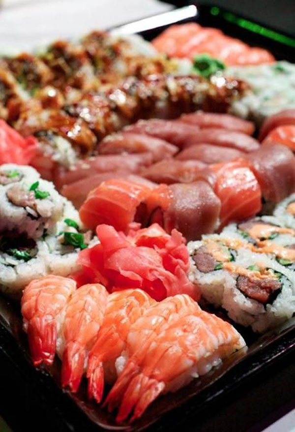 A table adorned with a tray full of sushi, tantalizing food porn for the hungry.