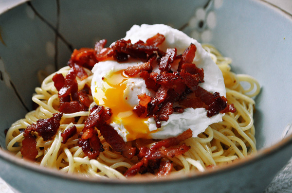 A mouthwatering bowl of pasta with bacon and an egg on top that will make you crave more.