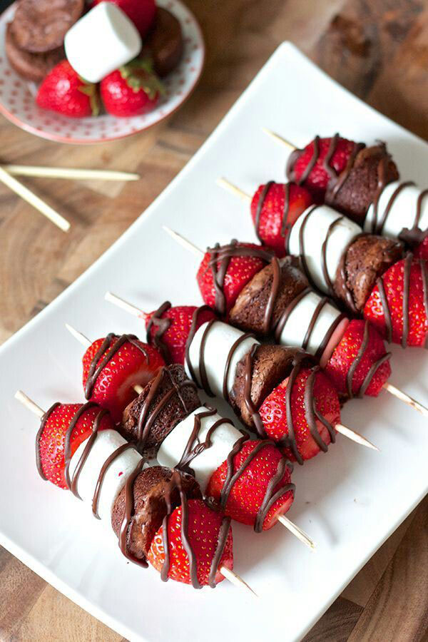 Chocolate strawberry skewers on a white plate serve as irresistible food porn.
