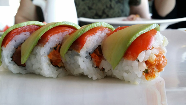 A mouthwatering plate of sushi adorned with fresh tomatoes and creamy avocado.