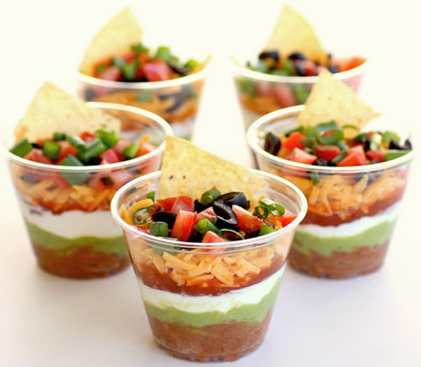 Game Day Grub Ideas: Mexican dips with chips and tortillas served in plastic cups, perfect for football gatherings.