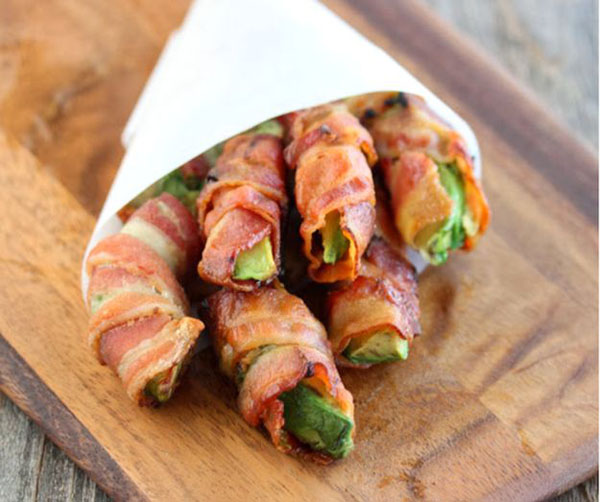 In Honor of Football, savor game day with bacon wrapped asparagus on a wooden cutting board.