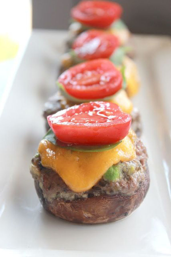 Game Day Grub Idea: Cheesy stuffed mushrooms with tomato served on a white plate.