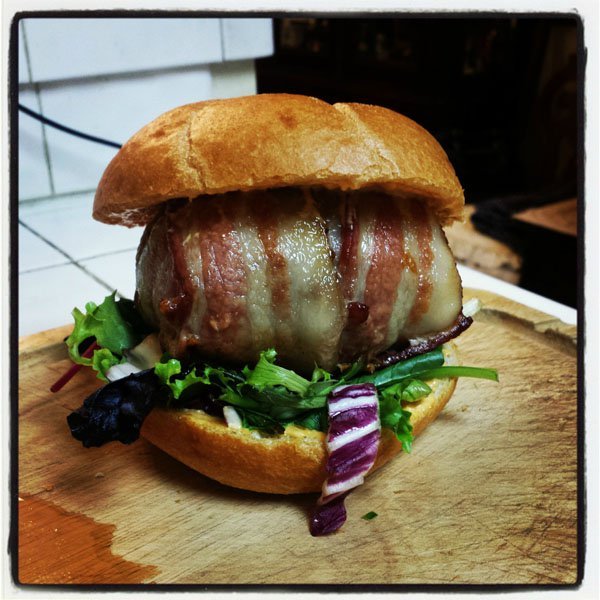 A mouthwatering bacon burger on a wooden cutting board that screams 