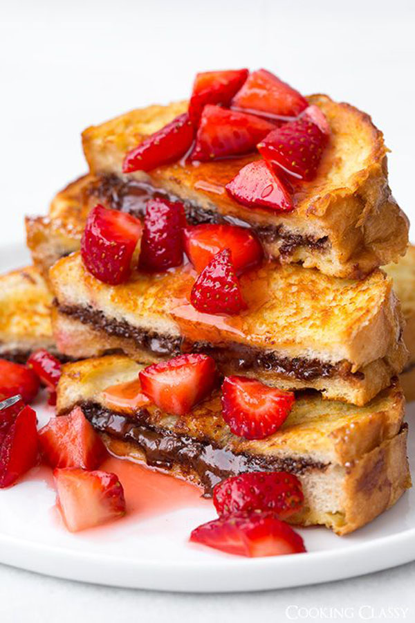 A mouthwatering stack of french toast with strawberries and chocolate sauce.