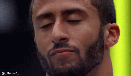 A bearded man, Colin Kaepernick, with his eyes closed.