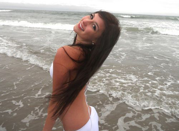A woman in a white bikini posing on the beach.