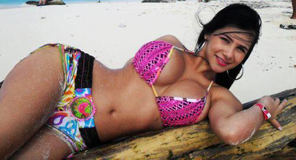 A woman in a bikini enjoying the sun on a log at the beach.