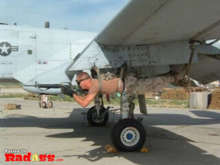 A man is laying on the side of an airplane, showcasing American Heroes.