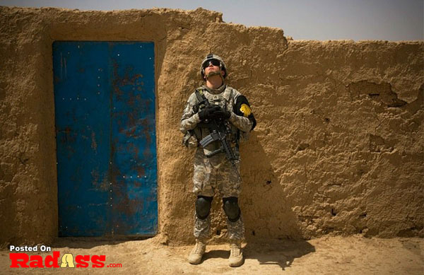 A soldier standing in front of a blue door, saluting and representing American Heroes.
