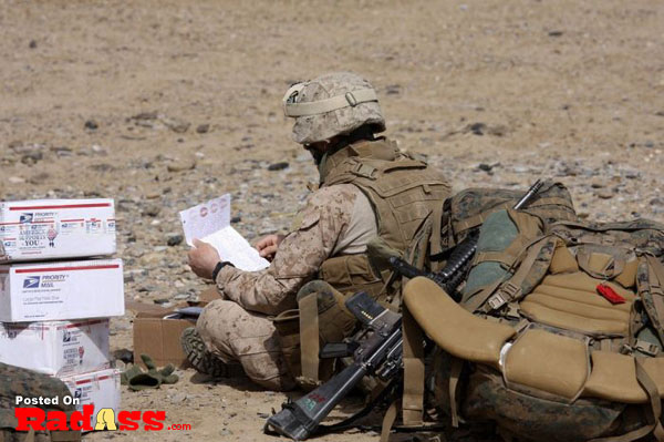 An American marine soldier is reading a letter on the ground, sharing gratitude and appreciation for their service.