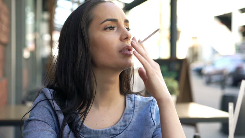 A young woman smoking a cigarette in an outdoor cafe discusses deal-breakers.