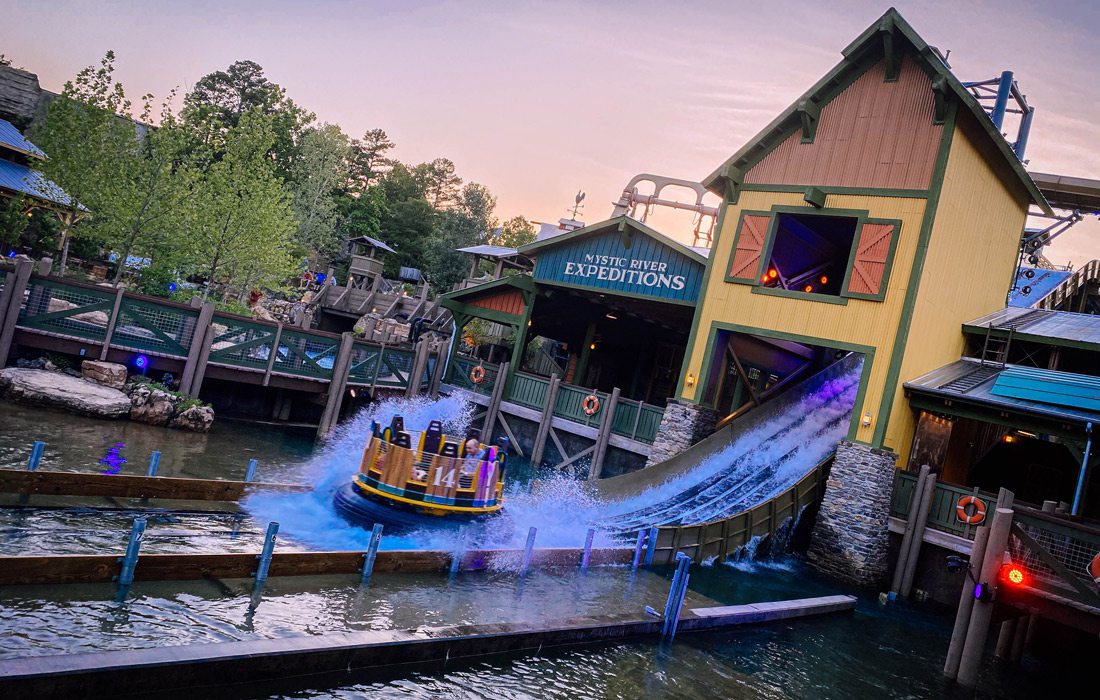An amusement park with a boat on the water.