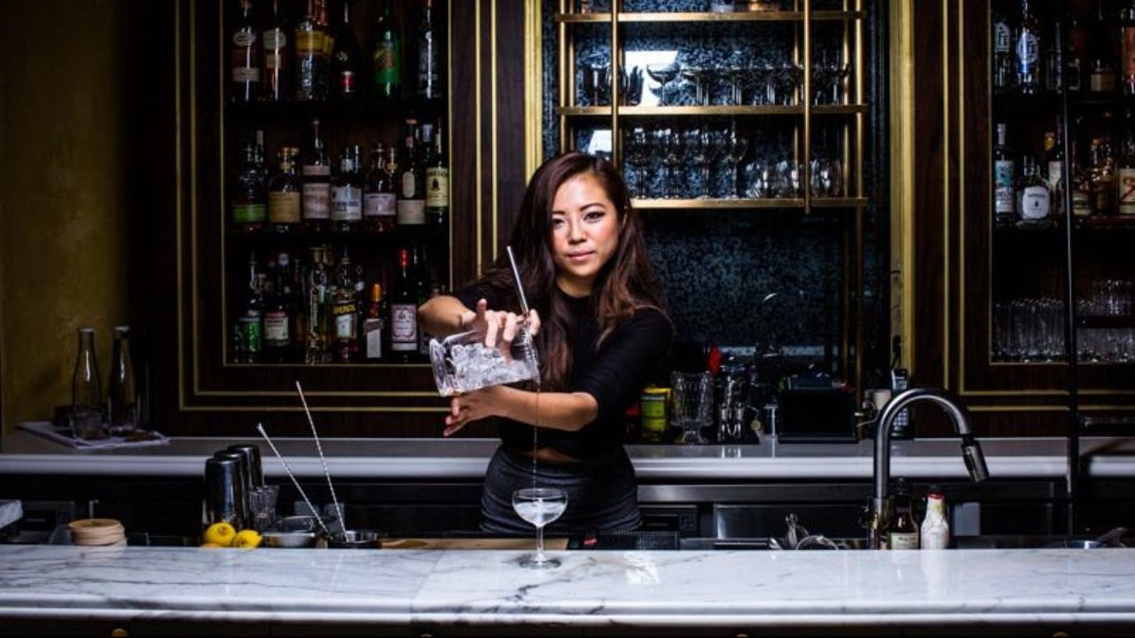 In this episode of "Tales from the Bar Side," a woman expertly crafts a drink, captivating everyone with her skill and precision behind the counter.