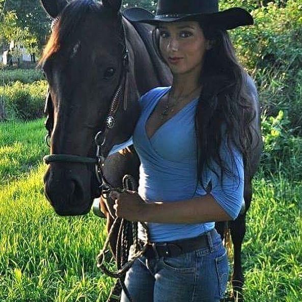 A woman in a cowboy hat posed with her horse.